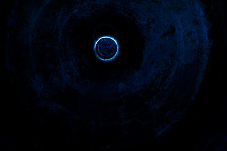 a blue circular light inside of a dark tunnel