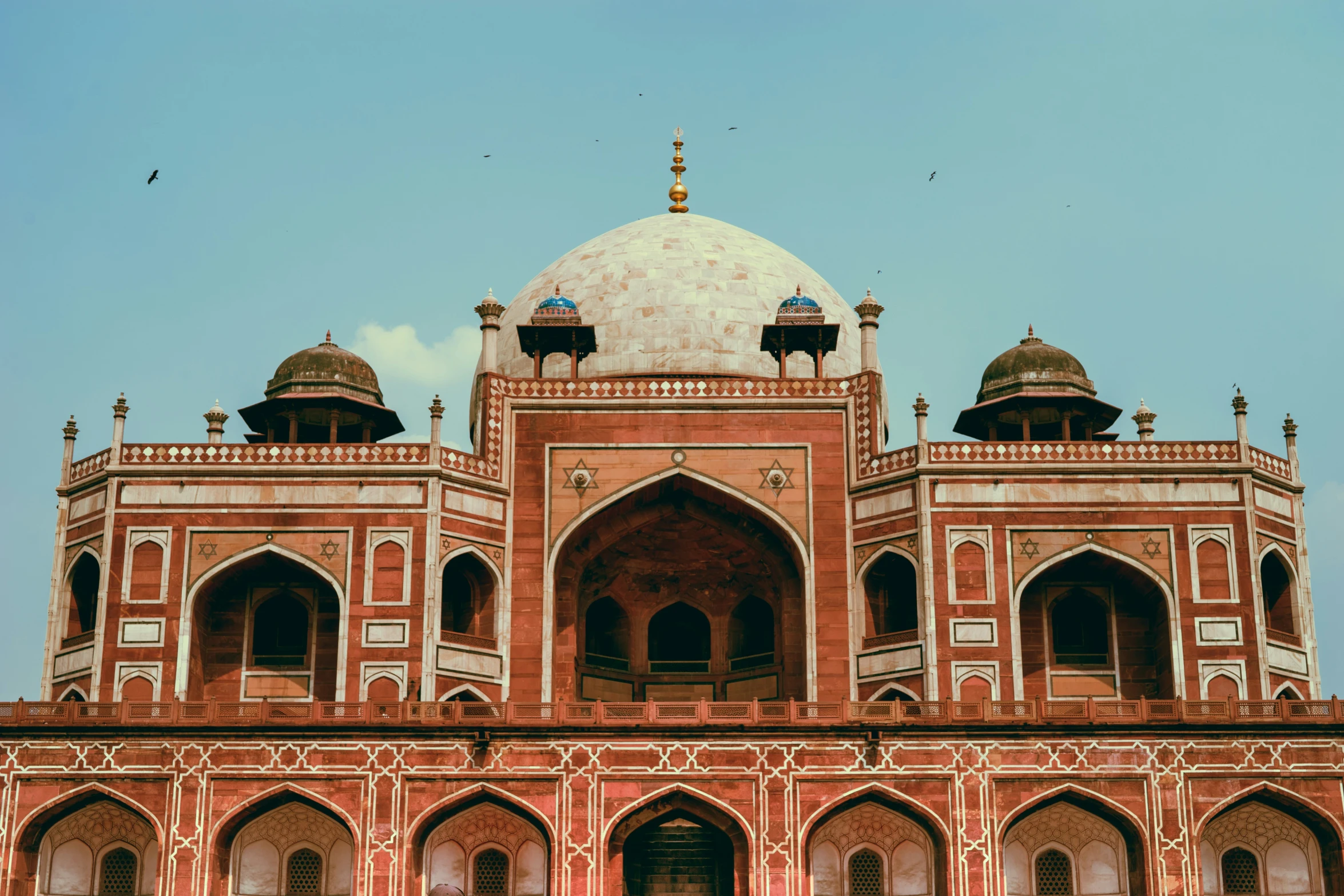 an ornate building with domes and arches and pillars on the top