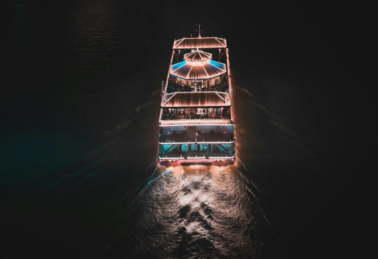 a boat with lights on is traveling at night