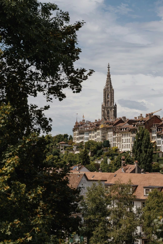 a building with a steeple sitting atop a tree covered hill