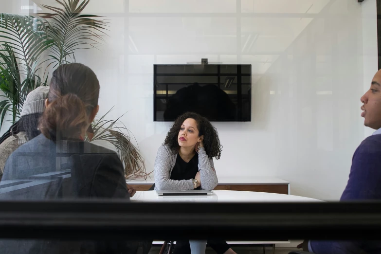 a woman sitting at a table talking to other people