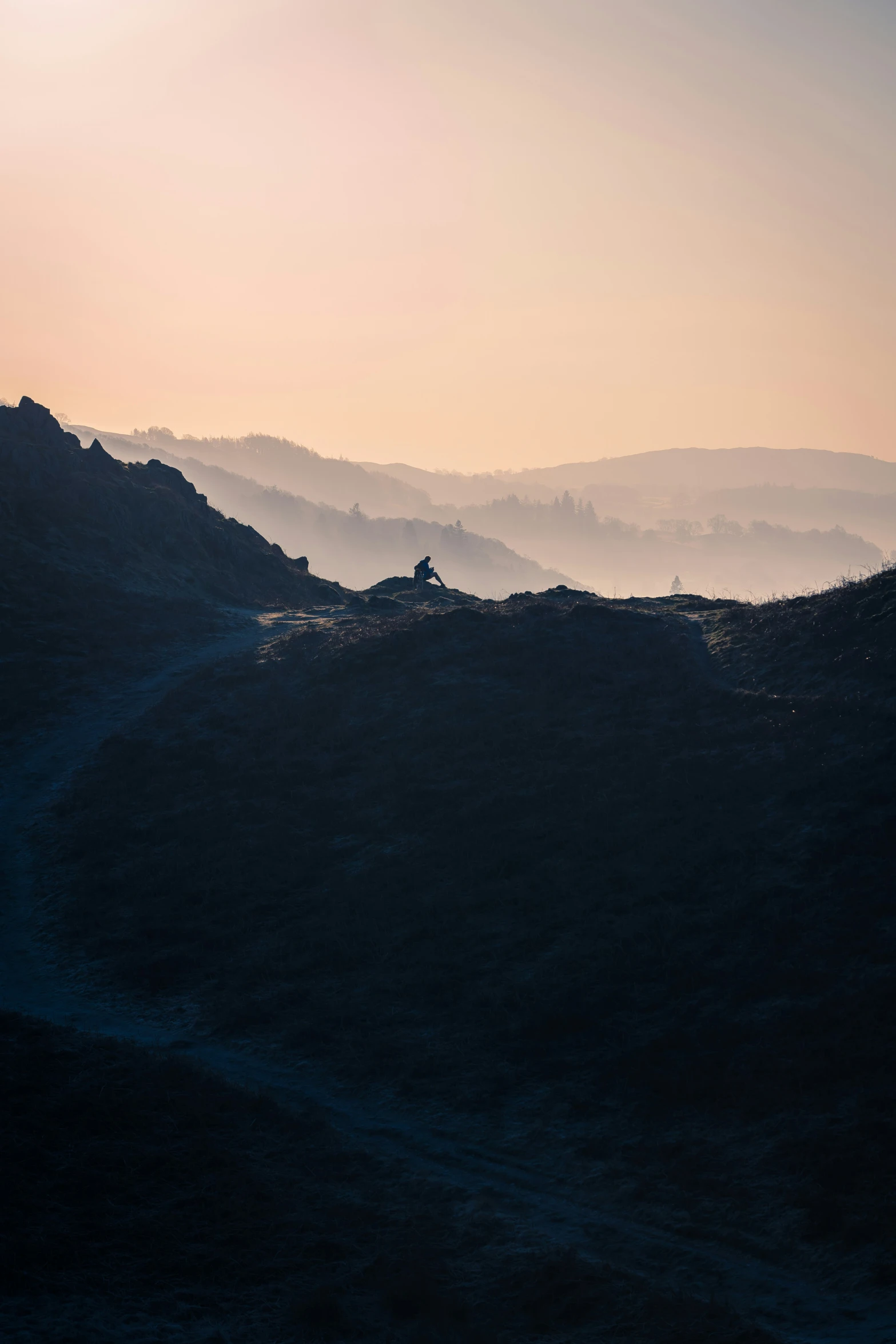 a view of a person on the mountain with sunset behind