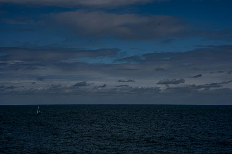 lone sailboat on calm blue ocean at dusk