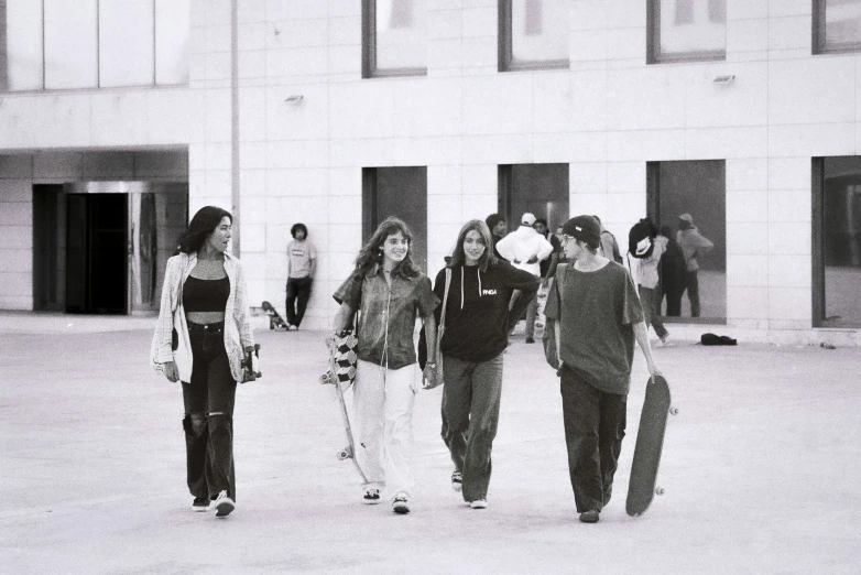 four skateboarders are walking together in a courtyard