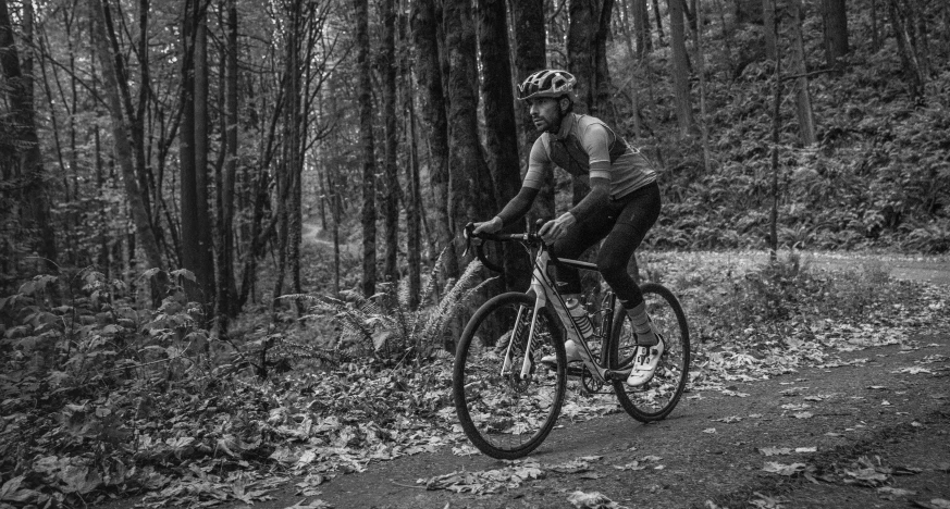 a man riding on the back of a bike through a forest