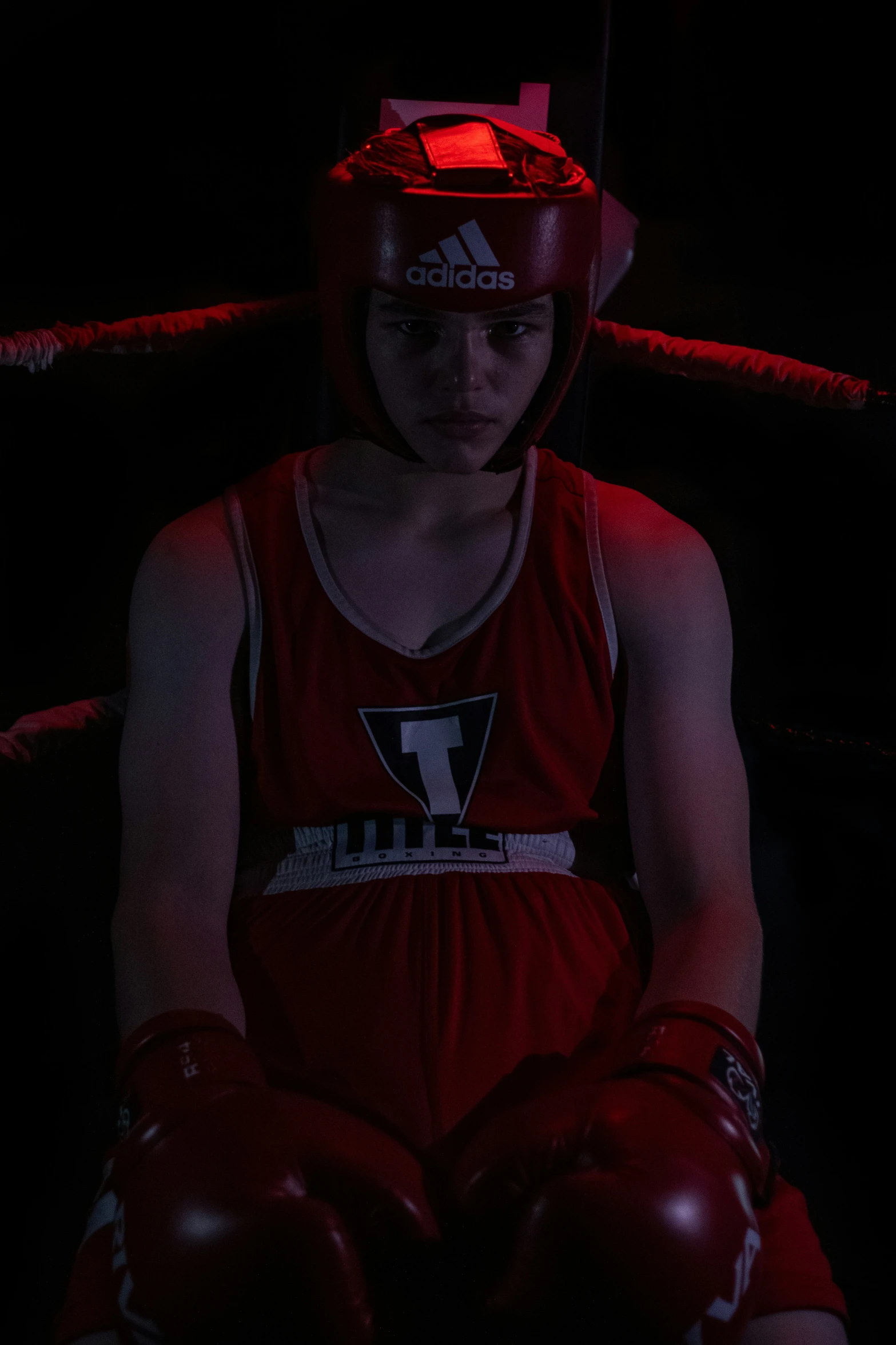 a young man sitting on a couch wearing red boxing gloves and a red helmet