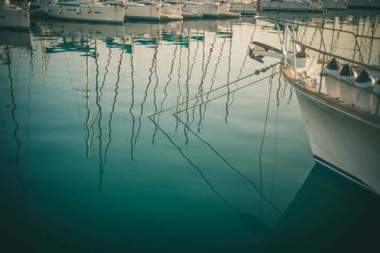 several boats are moored in a harbor as the sun reflects on water