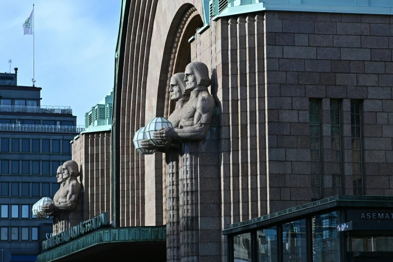 some statues are hanging off the side of a building