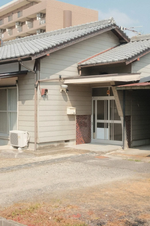 a man walking along the side walk past a building with several doors