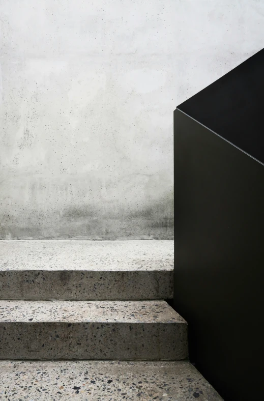 two black boxes sitting on concrete steps in front of a cement wall