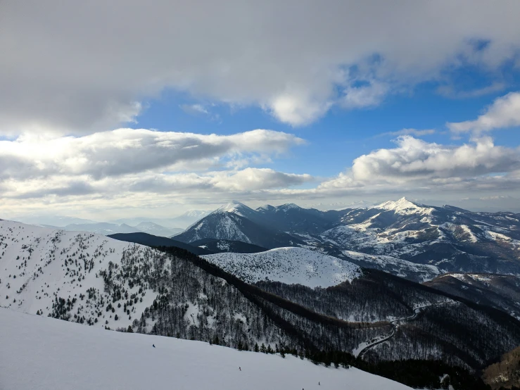 a lone snowboarder is standing on the mountain top