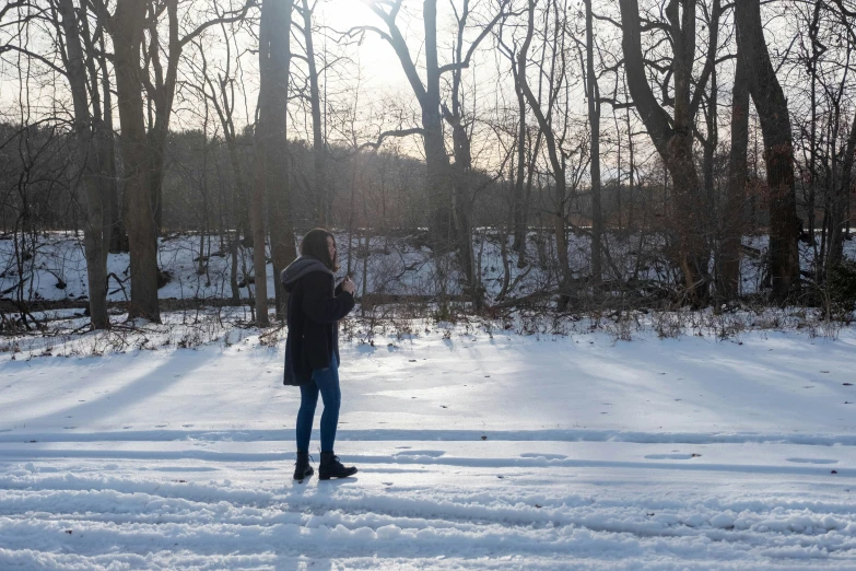 the snow is covering the ground, the person is using his phone