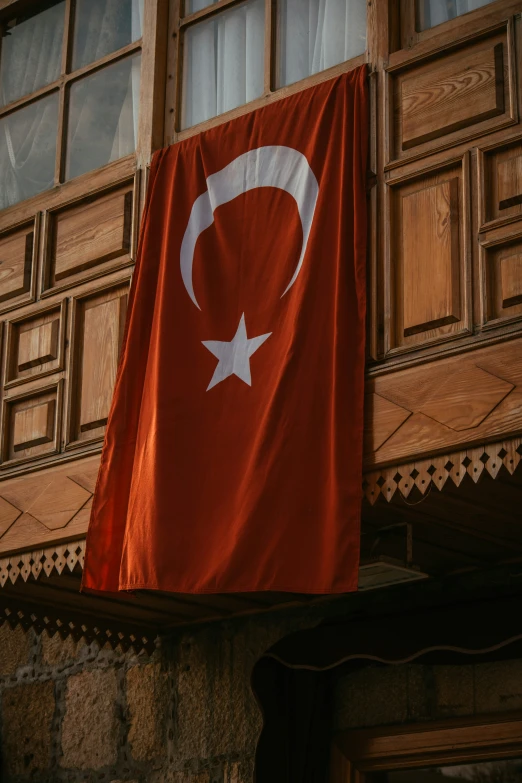 a turkish flag hung on a building with a window in the background