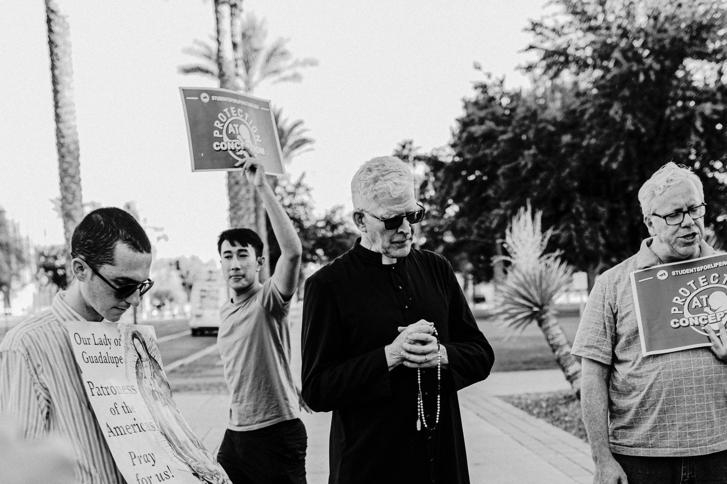 three men and one is standing on the sidewalk