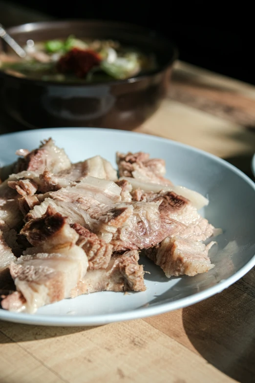 a bowl of chopped meat sitting next to a table