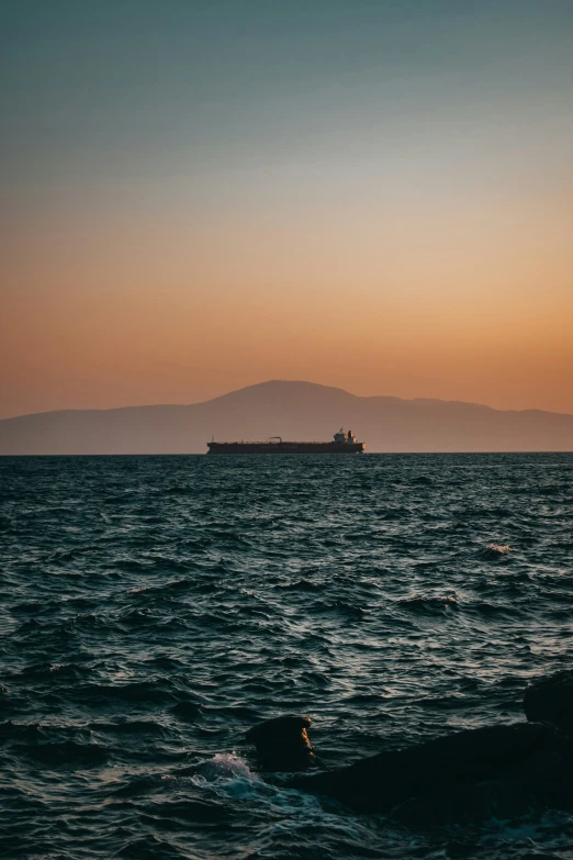 a ship sailing in the distance with hills in the background