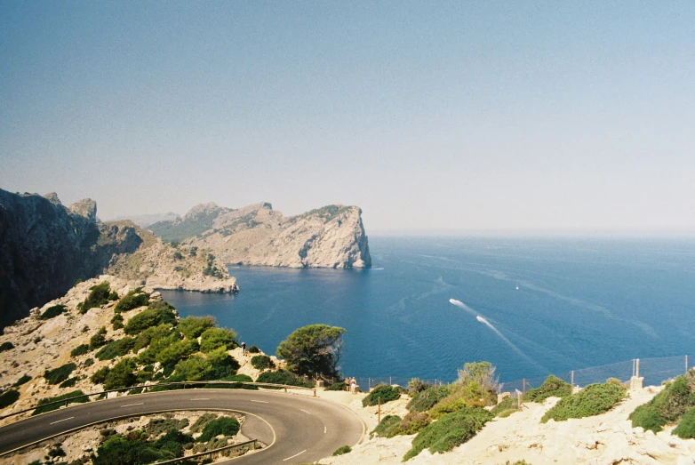 a winding road next to the beach and a mountain