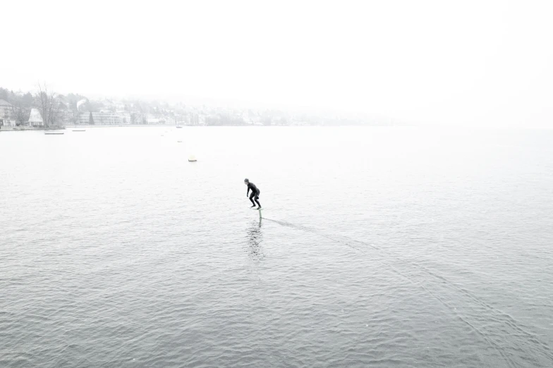 a man riding skis across a lake on top of a cloudy day