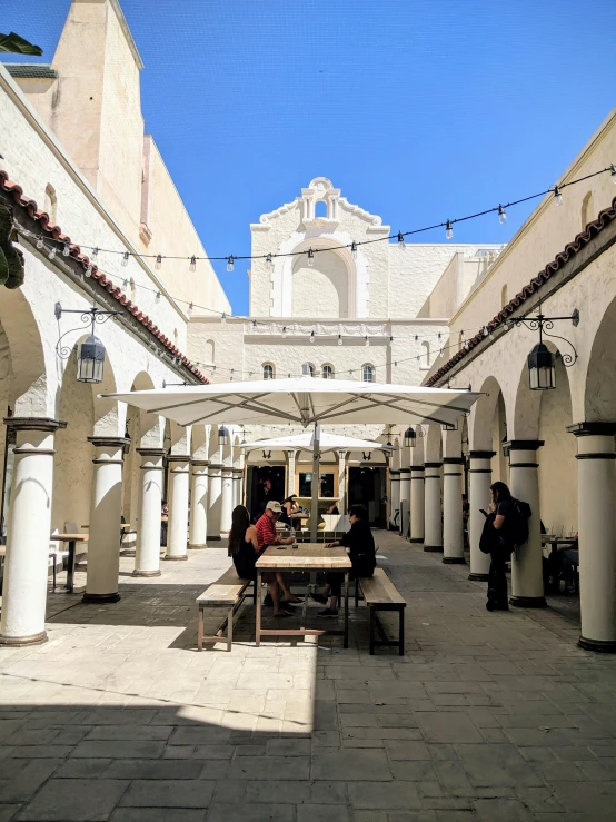 people sit at picnic tables between several pillars