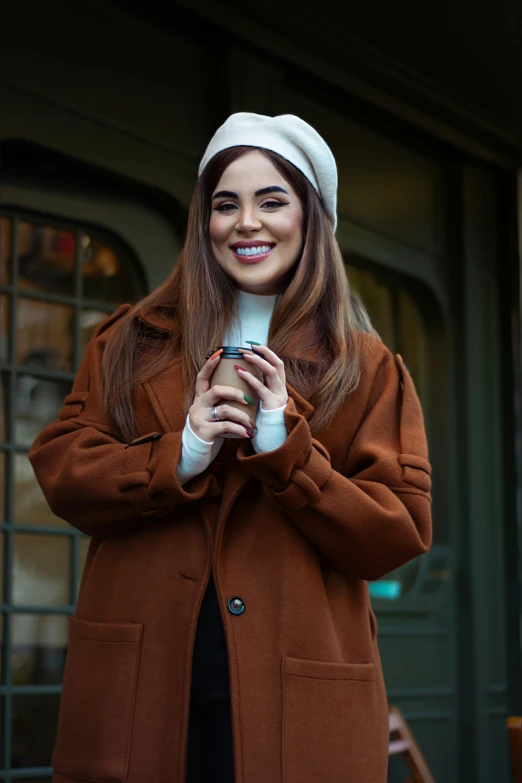 young woman in hat holding cup and cell phone