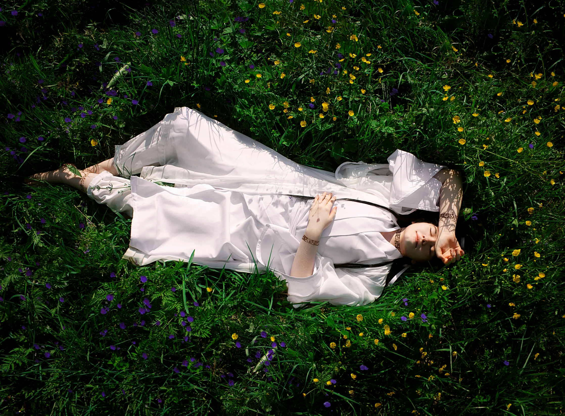 a lady is lying in the field with flowers