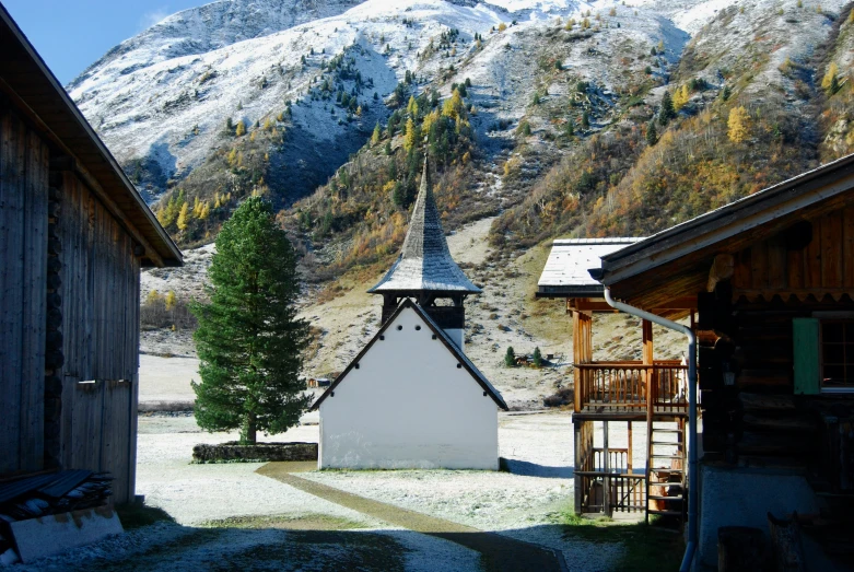 a small white house with mountains in the background