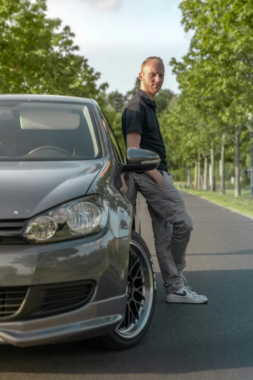 the man stands next to the car looking at his phone