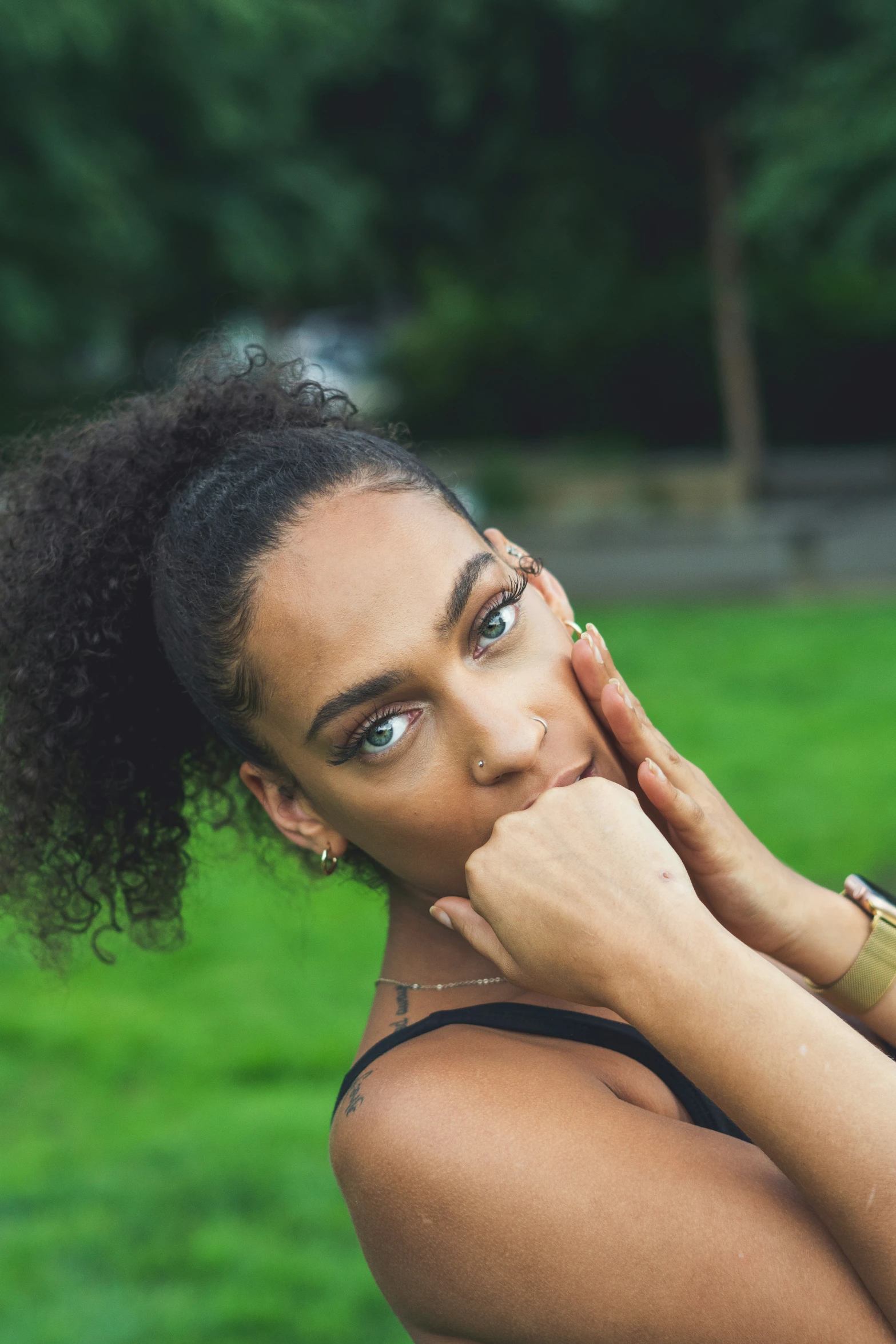 a woman sitting in the grass holding her hands on her chin