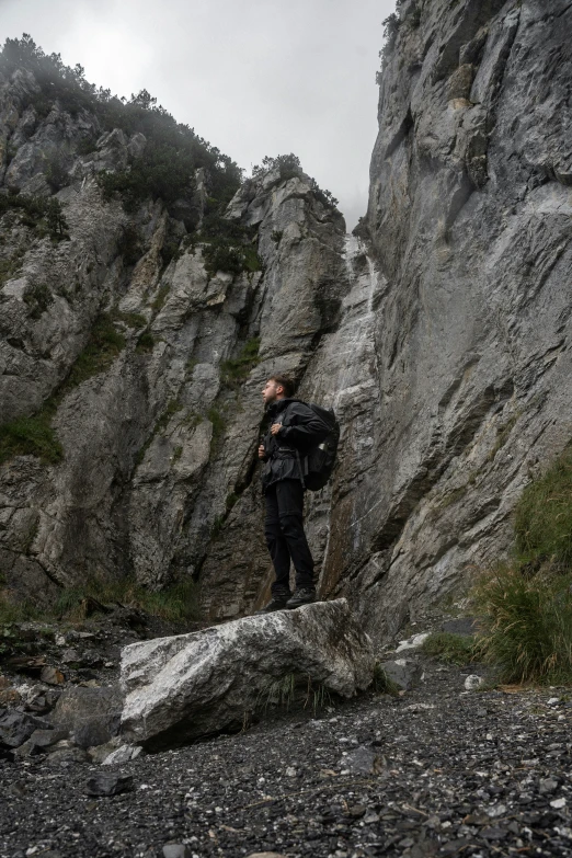 a man climbing on some rocks with a mountain behind him