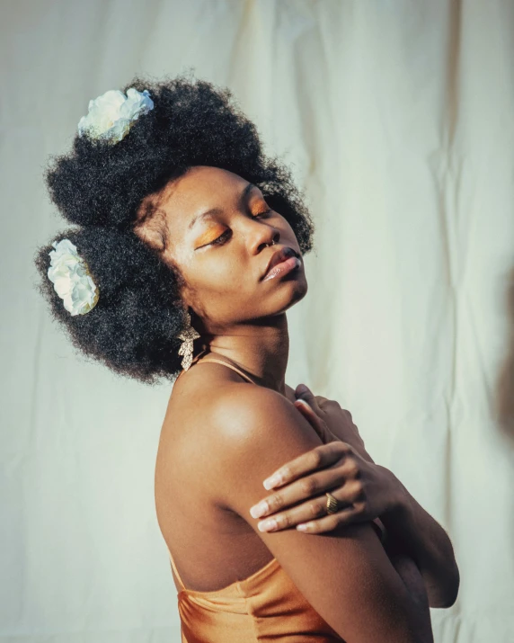 woman with flowers in her hair standing against white wall