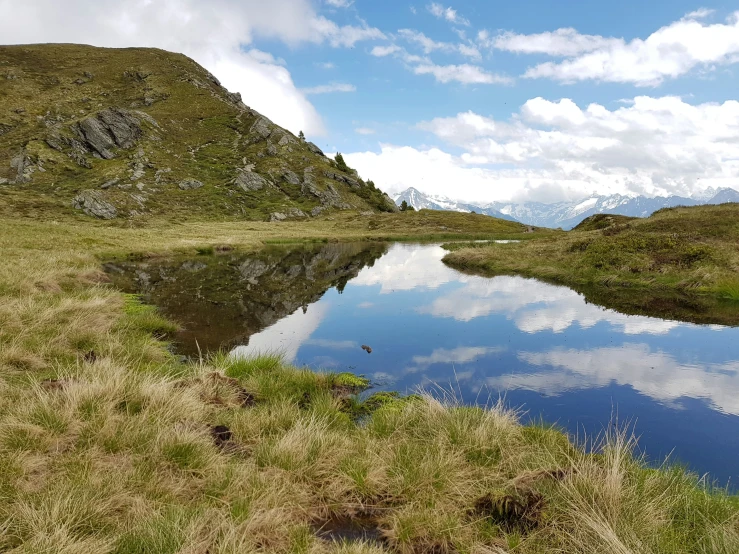 a mountain with green grass and lots of water