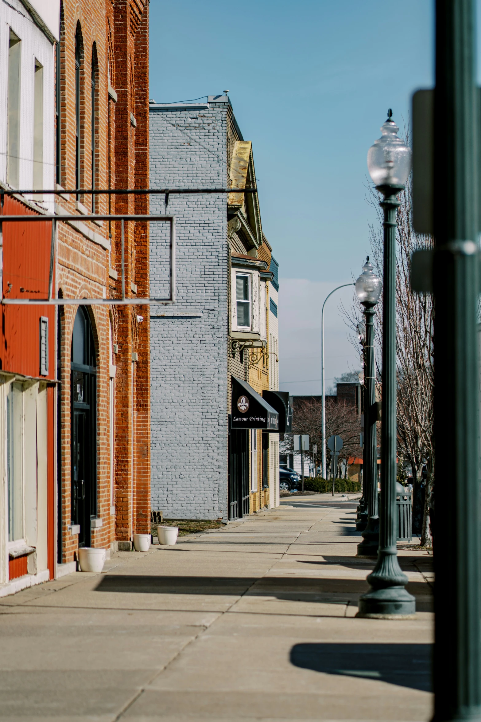 a sidewalk lined with stores lined up against brick buildings