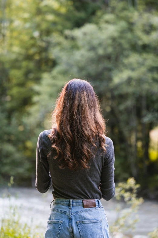 a woman standing in the woods alone and looking into a stream