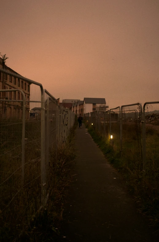 a fence with buildings in the background as seen from an alley