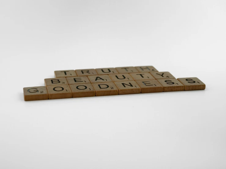 a scrabble game sitting on a table with blocks spelling the word truth and beauty goodness