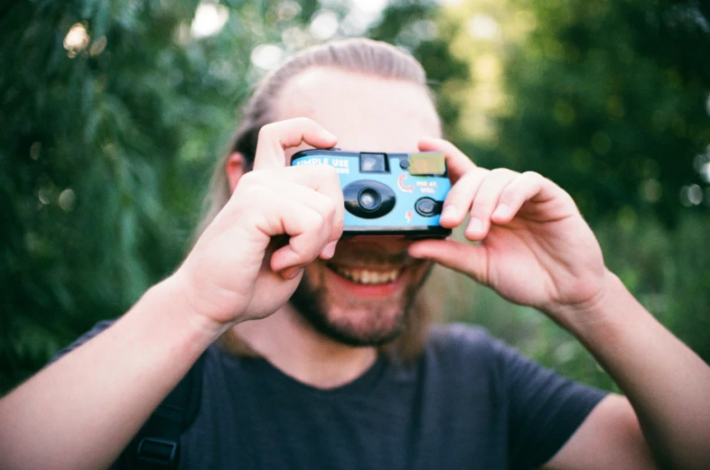 a man holding up a camera to look into the camera