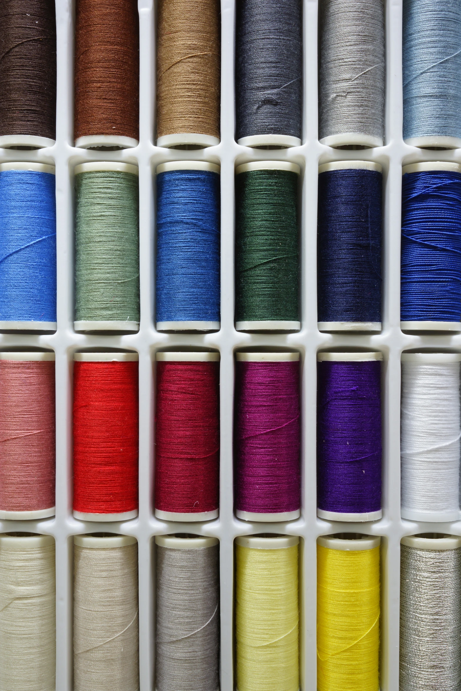 an assortment of spools of shiny colored thread