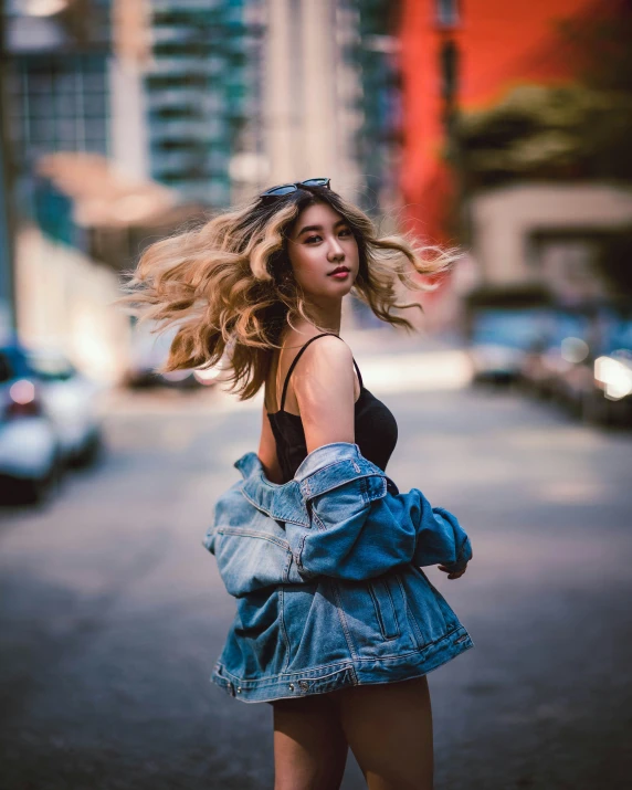 the woman is walking down the road wearing jeans