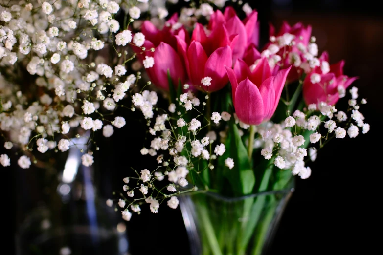 some pink tulips and white flowers in a glass vase