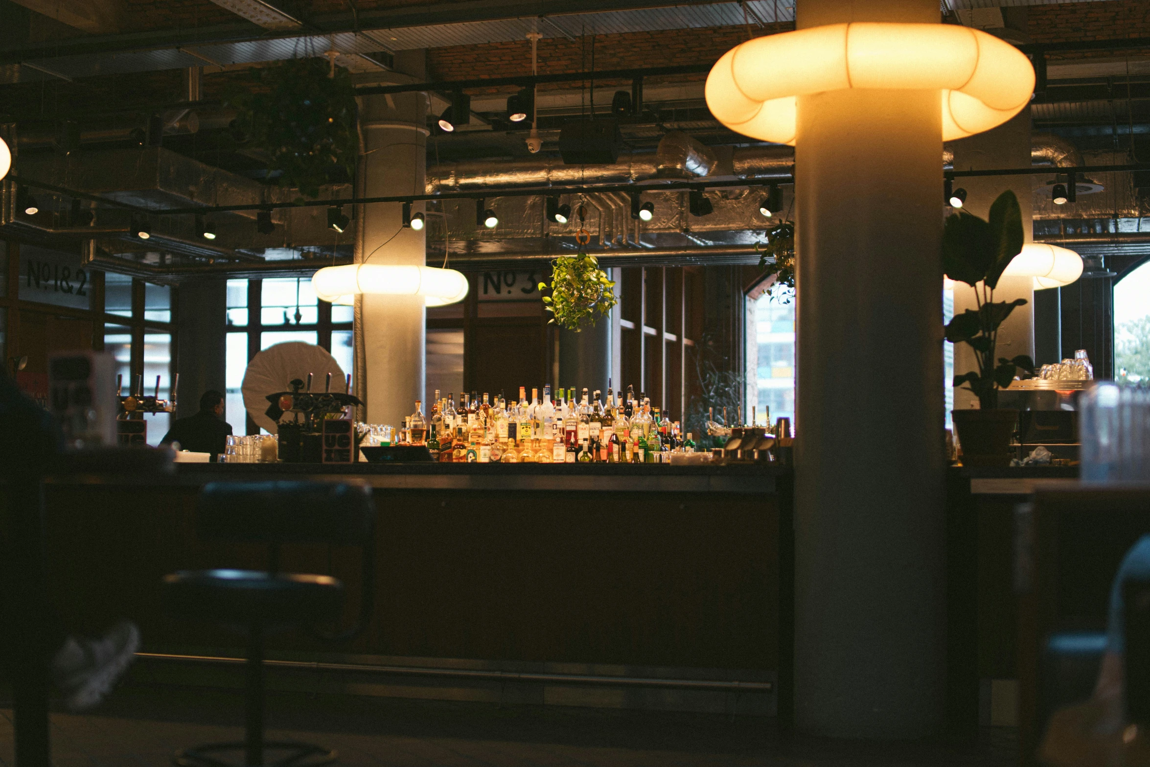 a bar is lit up by lights and a number of stools