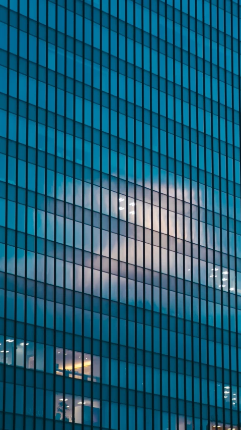 a building's window reflects the cloudy sky