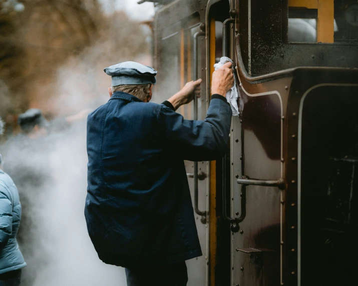 a person putting on a hat next to a train
