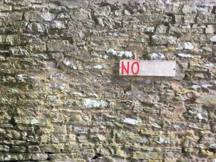 a sign that says no next to a stone wall