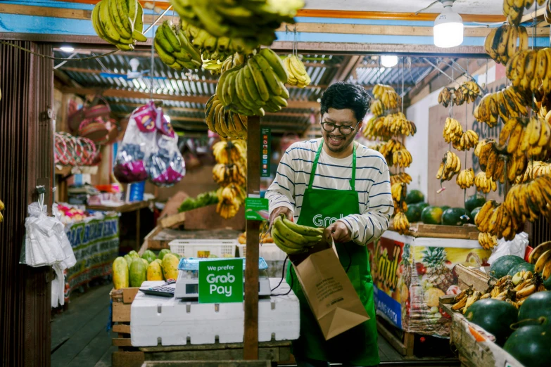 a man standing by some bananas in a store