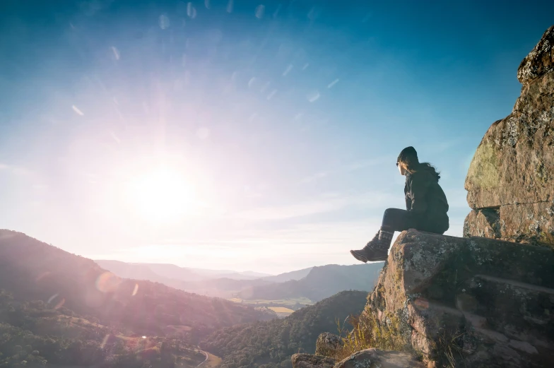 a person sitting on top of a large rock