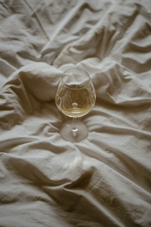 a small wine glass on a bed sheet