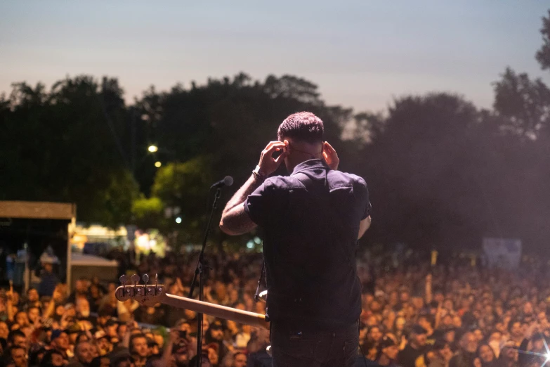 a man stands in front of a large audience as he talks on a cell phone