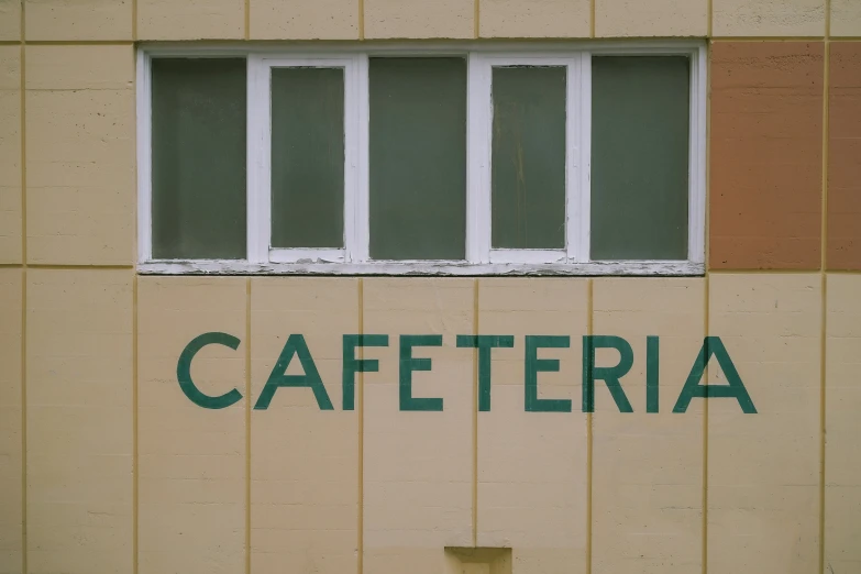 the letters caferia are made of wood, while an orange brick wall is painted a pale yellow