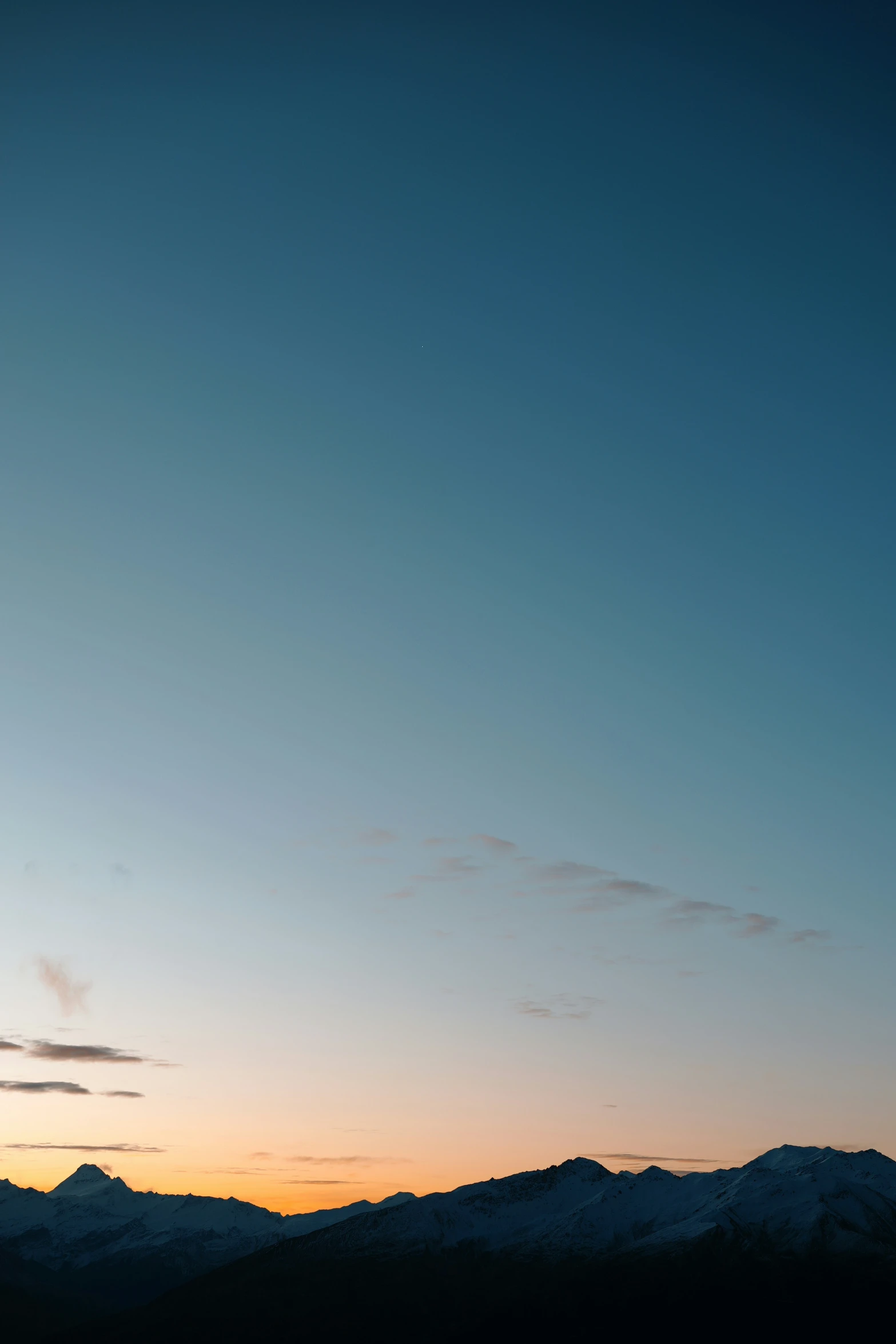 the silhouette of a plane flying above the mountains