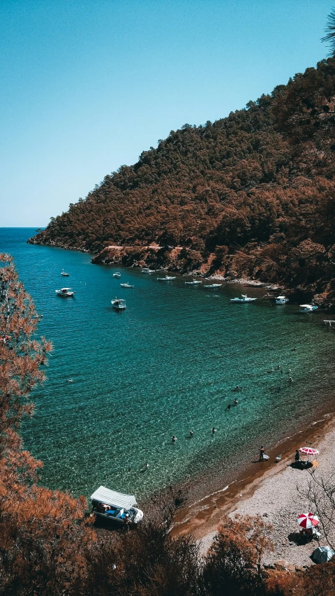 a beach that is lined with boats and green mountains